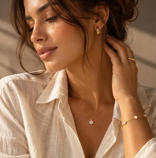 Mulher de camisa branca com colar ponto de luz, brinco e pulseira dourados